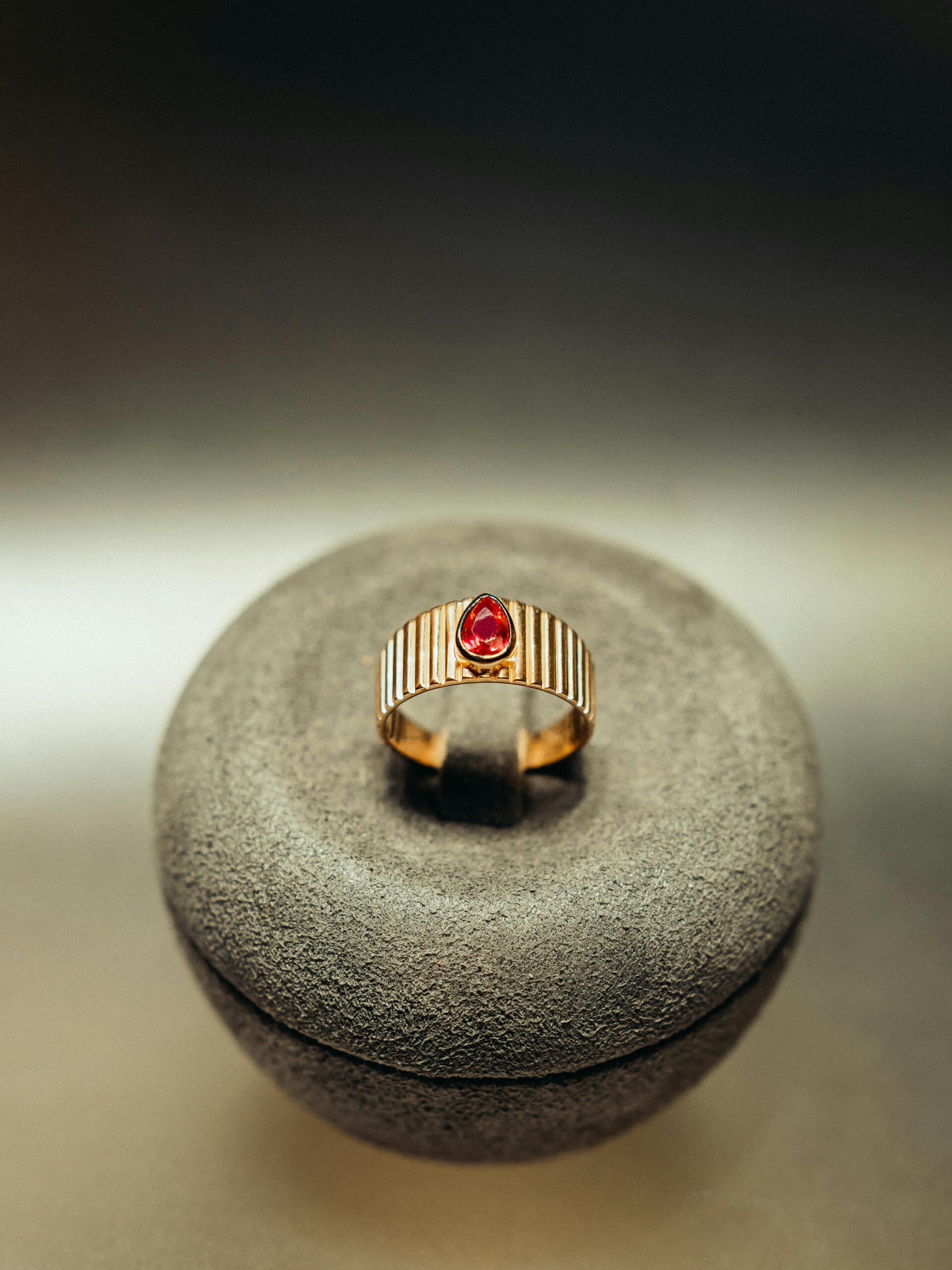 A sophisticated gold ring featuring a striking red gemstone, perfect for jewelry lovers.